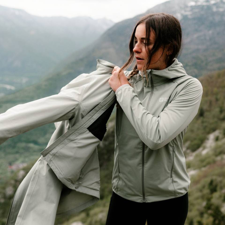 Hiker in a foggy mountain landscape puts on a rain jacket